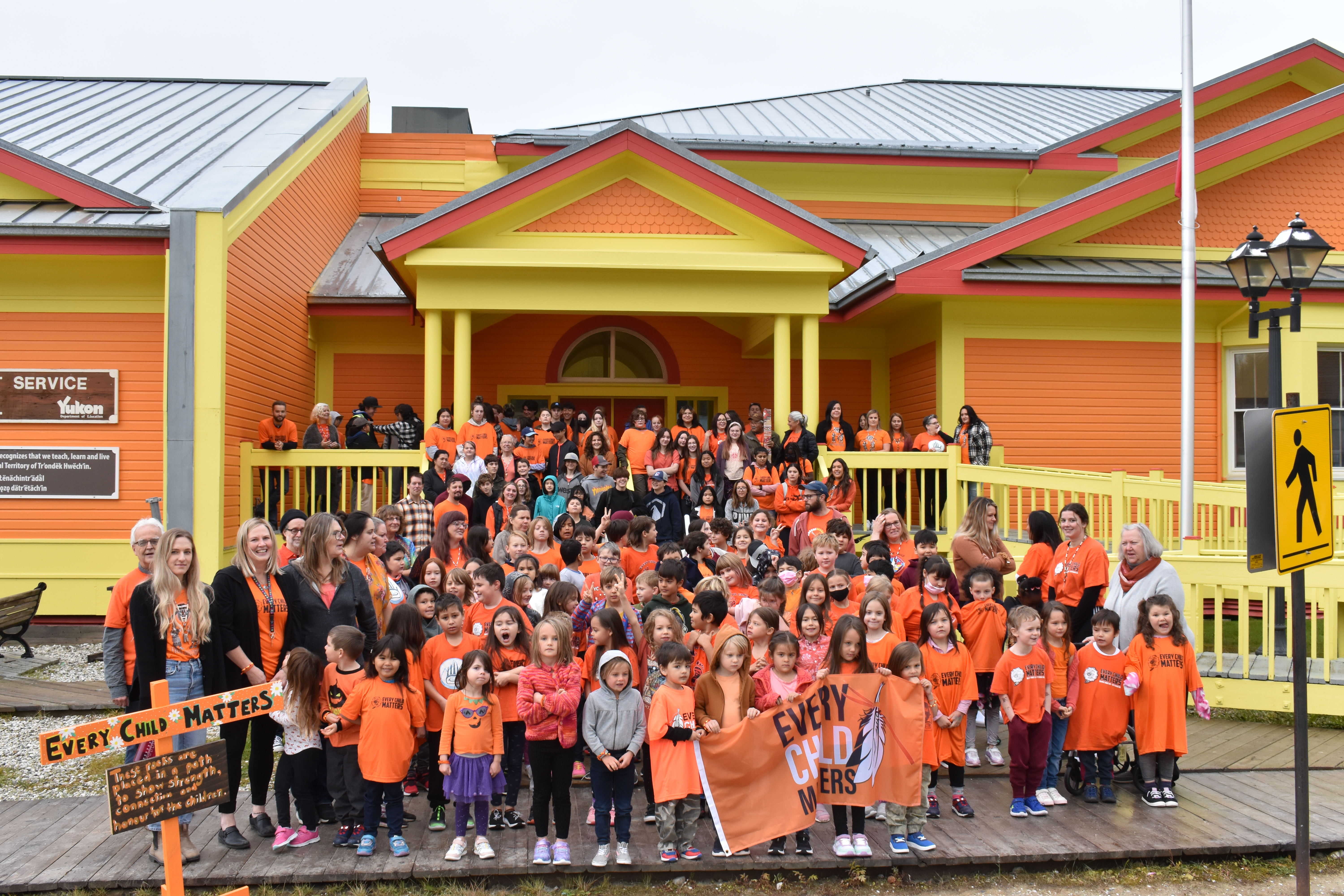 Students gather in orange in front of their school 