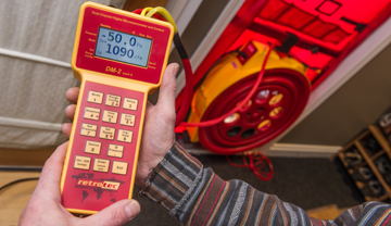 Man holding electronic meter hooked up to fan in sealed doorway