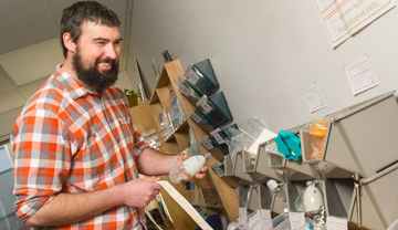 Man taking a low flow shower head from bins of energy efficient items