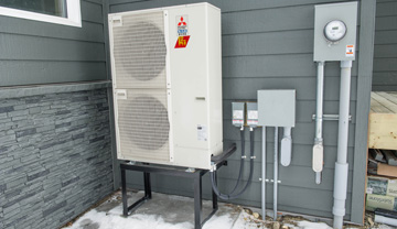 An air source heat pump on the outside wall of a house.