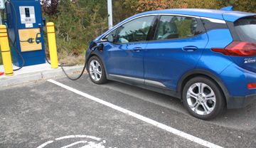 Voiture électrique bleue branchée à une borne de recharge publique.